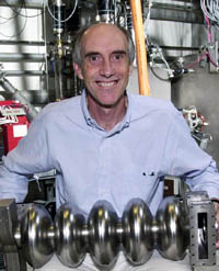 Gwyn Williams holding a 5-cell cavity inside JLab's FEL